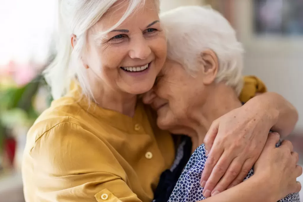 Two smiling AgeWell community members hugging